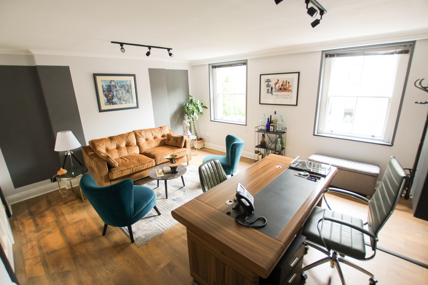 Modernes Büro mit Sofa, Sesseln und Schreibtisch.